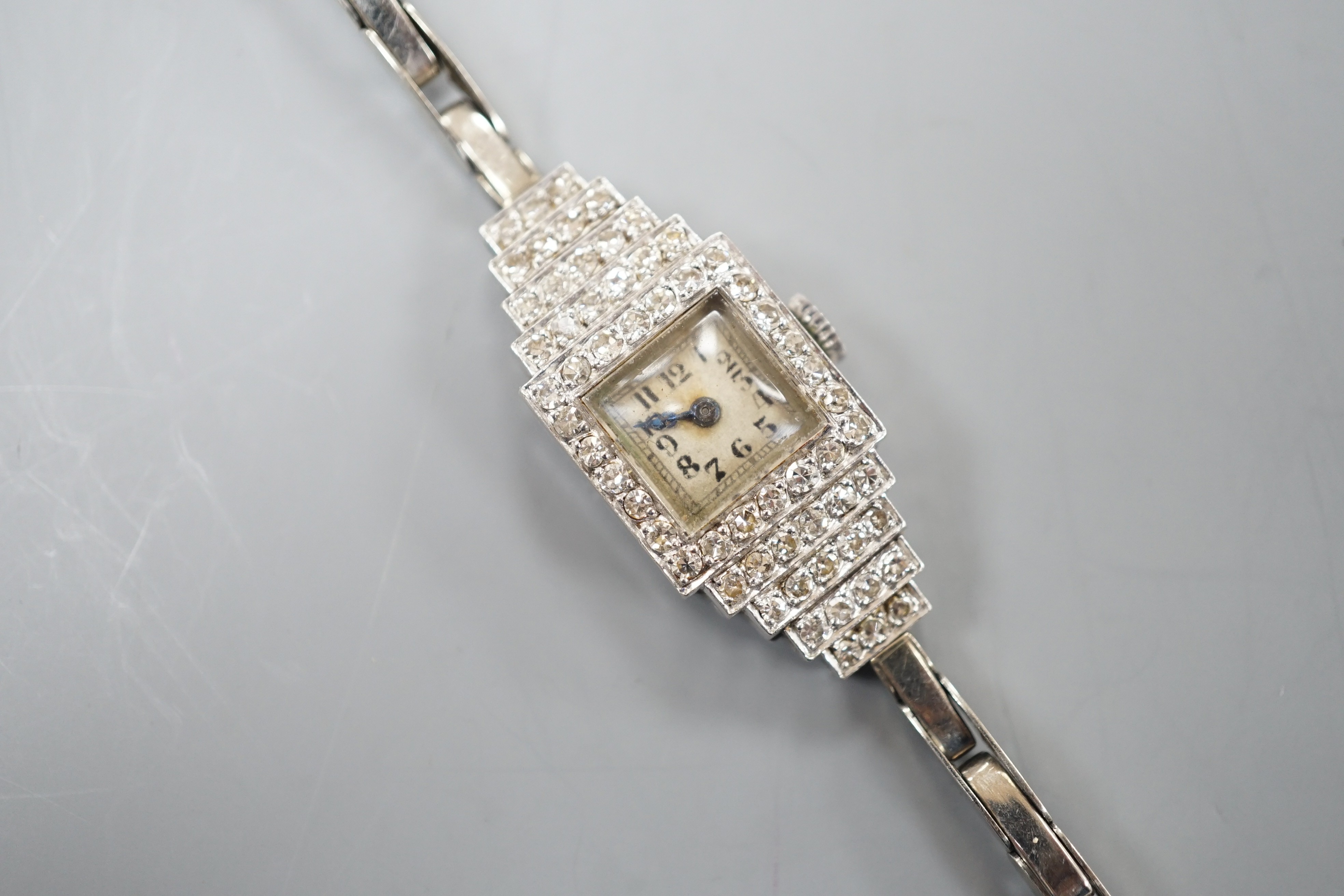 A lady's mid 20th century white metal (stamped platinum) and diamond cluster set Vertex cocktail watch, with stepped lugs, on a 9ct white metal expanding bracelet, 15.5cm, gross weight 15.6 grams.